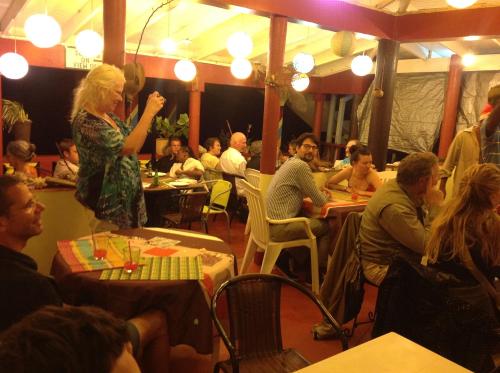 a group of people sitting at tables in a restaurant at Rainbow Beach Apartment in Calibishie
