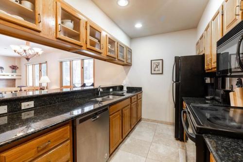 a kitchen with wooden cabinets and a black refrigerator at Townsend Place Ski In Ski Out Access in Beaver Creek