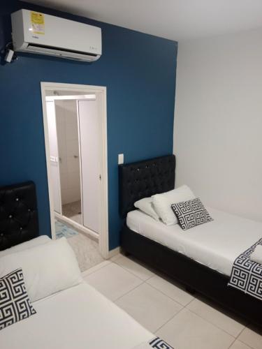 two beds in a room with a blue wall at Mar de Indias House in Cartagena de Indias