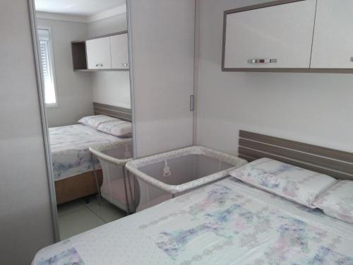 a room with two beds and a mirror at Apto Aconchego da Serra - Bairro Maria Goretti in Bento Gonçalves