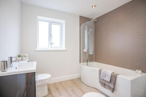 a bathroom with a tub and a toilet and a sink at Stylish New Bungalow - Ideal for up to 10 in Welney