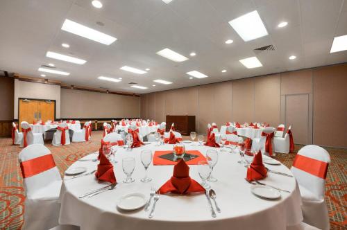 a banquet hall with white tables and red chairs at Red Lion Hotel Gillette in Gillette