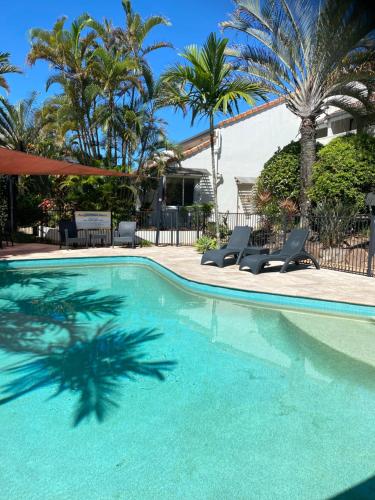 una piscina con dos sillas y palmeras en Peregian Court Resort apartment number 21, en Peregian Beach