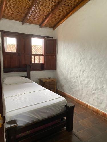 a bedroom with a bed and two windows in it at Mi Casa en Barichara in Barichara