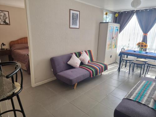 a living room with a purple couch and a table at Hermoso departamento, cómodo y tranquilo, cerca de todo, a pasos de la playa in Iquique