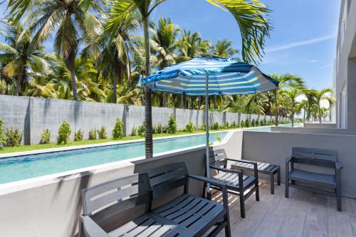 a patio with chairs and an umbrella next to a swimming pool at Beach front Blue Summer Apartment Costa Del Sol in El Zapote