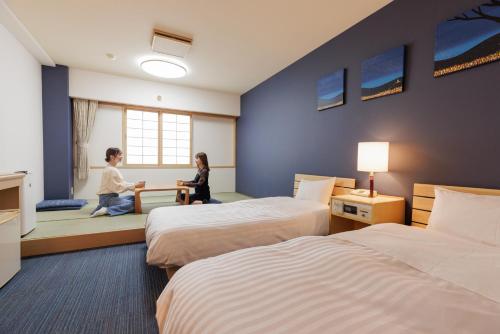 Dos personas sentadas en una habitación de hotel con dos camas en Ashibetsu Onsen Starlight Hotel en Ashibetsu