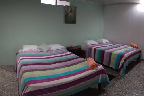 duas camas com cobertores riscados num quarto em Habitacion en Bijagua em Bijagua