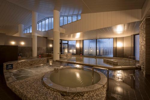 a large bathroom with a tub in a building at Ashibetsu Onsen Starlight Hotel in Ashibetsu