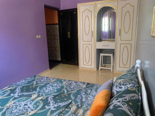 a bedroom with purple walls and a bed and a mirror at AMRAOUI Apartment in Rissani