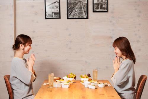 two girls sitting at a table with their hands up at Ashibetsu Onsen Starlight Hotel in Ashibetsu