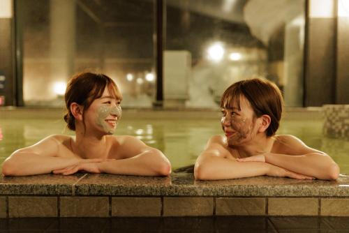 two men laying in a swimming pool with masks on their faces at Ashibetsu Onsen Starlight Hotel in Ashibetsu