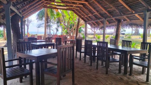eine Reihe von Tischen und Stühlen in einem Restaurant in der Unterkunft Hotel Coral Bay in Trincomalee