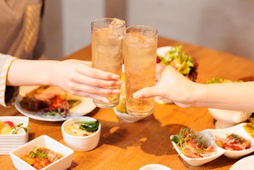 two people are holding champagne glasses on a table with food at Ashibetsu Onsen Starlight Hotel in Ashibetsu
