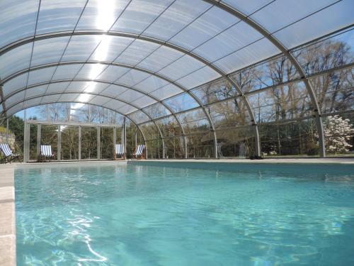 an indoor swimming pool with a glass roof at Cèdre et Charme in Saint-Branchs