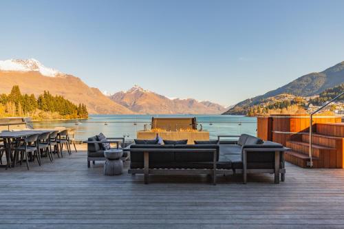 a wooden deck with tables and chairs and a body of water at Eichardt's Private Hotel in Queenstown