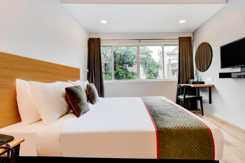 a bedroom with a large white bed and a window at Townhouse Century Hotel in Nagpur