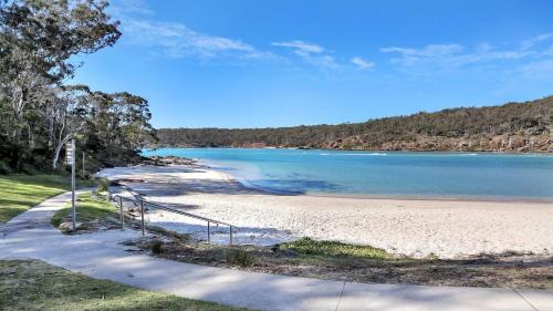 a beach with a staircase leading to the water at 27 Kanangra Street Pambula Beach in Pambula Beach