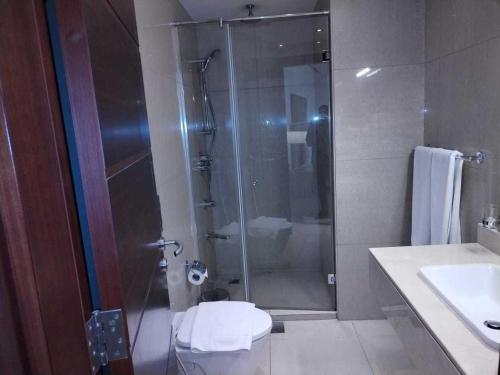 a bathroom with a shower and a toilet and a sink at SPOT ON Gagan Hotel in Khatauli