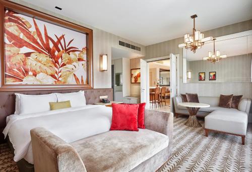 Resorts World Sentosa - Equarius Hotel في سنغافورة: غرفة فندقية بسرير كبير واريكة