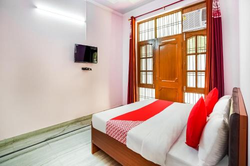a bedroom with a bed with red pillows and a window at OYO Hotel Royal Inn in Faridabad