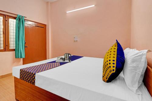 een slaapkamer met een bed met een geel en blauw kussen bij SPOT ON Ganpati Home Stays in Dehradun