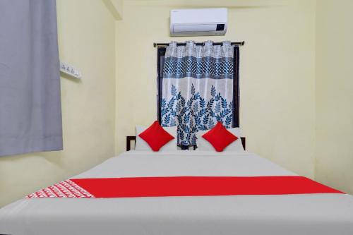 1 dormitorio con cama blanca y almohadas rojas en OYO Ruby Grand Inn Nallagandla, en Lingampalli