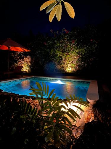 a swimming pool at night with an umbrella at PINOKKIO B&B Restaurant in Jimbaran