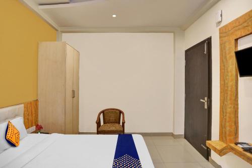 1 dormitorio con cama, puerta y silla en SPOT ON Hotel Harmony en Muthiganj