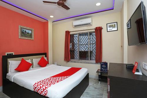 een slaapkamer met een bed met rode muren en een televisie bij OYO Hotel Chinar in Dum Dum