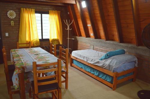 a bedroom with two beds and a table and chairs at Complejo de Cabañas Valentino in Embalse