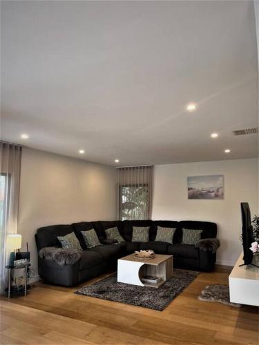 a living room with a black couch and a table at Unique 3 Bedroom House close to Merewether Beach in Merewether