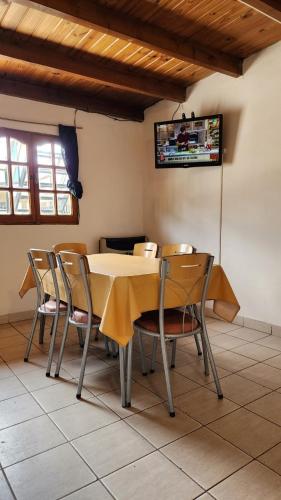 mesa de comedor con sillas y TV en la pared en Hospedaje Belen en Ushuaia