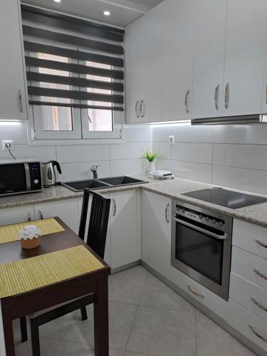 a kitchen with white cabinets and a table and a stove at Cozy Apartment in Nea Palatia-Oropos in Oropos