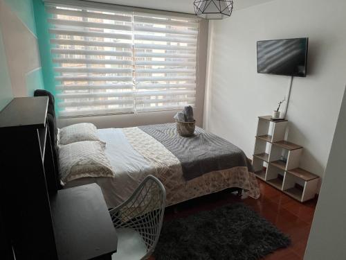 1 dormitorio con 1 cama y ventana con TV en Habitación cerca aeropuerto el Dorado, en Bogotá