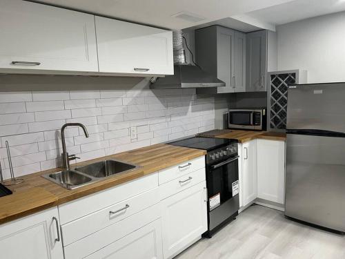 uma cozinha com armários brancos e um frigorífico de aço inoxidável em Cozy 1 BR basement apartment with Free Street Parking & Separate Entrance em Milton