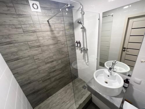 uma casa de banho com uma cabina de duche em vidro e um lavatório. em Элитная квартира в центре em Pavlodar