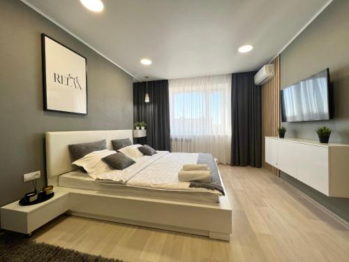 1 dormitorio con 1 cama grande y TV de pantalla plana en Элитная квартира в центре, en Pavlodar