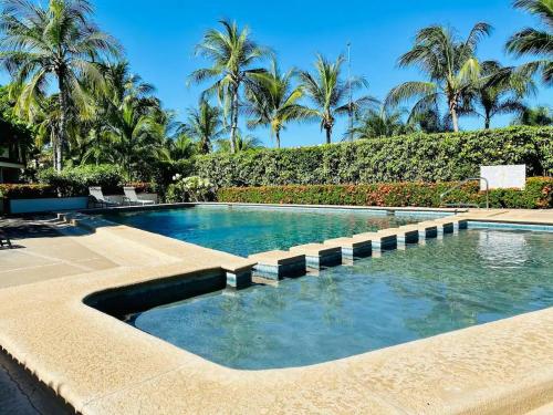 una piscina en un complejo con palmeras en Villa Flamingo 8 at Playa Flamingo, en Playa Flamingo