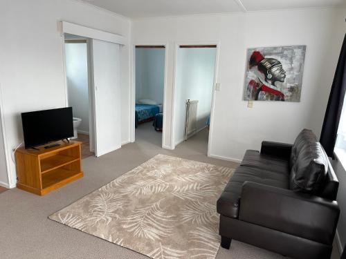 a living room with a couch and a flat screen tv at MALFROY Motor Lodge Rotorua in Rotorua