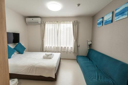 a bedroom with a bed and a couch and a window at PLEASANT STAY Sunayama in Miyako-jima