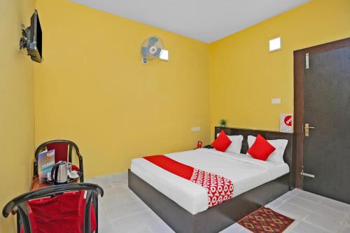 a bedroom with a bed with yellow walls and red pillows at OYO Seven Inn in Bhubaneshwar