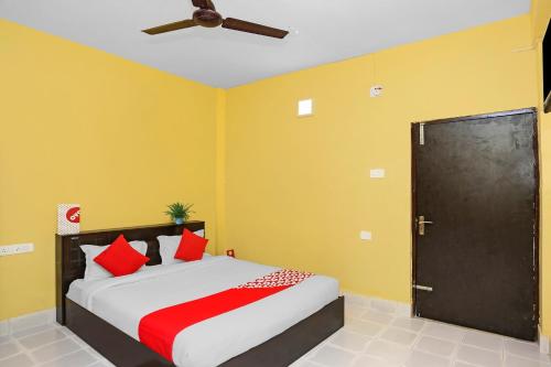 um quarto com uma cama com paredes amarelas e uma ventoinha de tecto em OYO Seven Inn em Bhubaneshwar