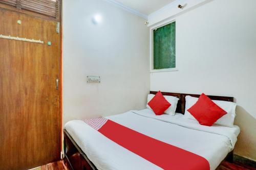 Ratiram Hotel Near Worlds of Wonder في Kālkāji Devi: غرفة نوم بسرير ومخدات حمراء وبيضاء