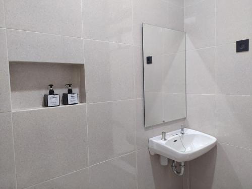 La salle de bains blanche est pourvue d'un lavabo et d'un miroir. dans l'établissement Urbanview Badran Residence Syariah Manahan, à Solo