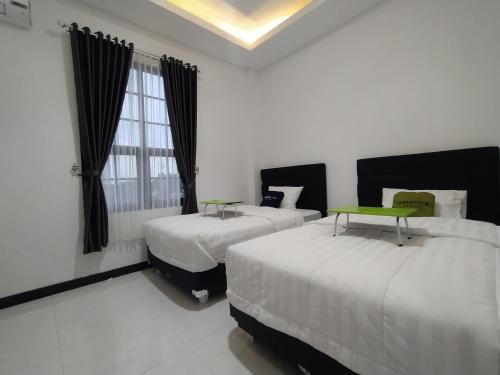 Habitación de hotel con 2 camas y ventana en Urbanview Badran Residence Syariah Manahan, en Solo