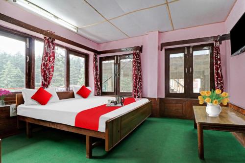 a bedroom with a large bed with red pillows at Hotel O Hema Holiday Home in Manāli