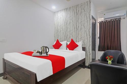 a bedroom with a bed with red pillows and a chair at Super OYO Alwal Residency in Hyderabad