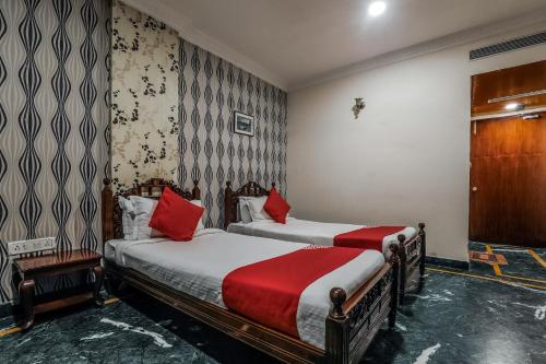 2 camas en una habitación de hotel con almohadas rojas en OYO Athithi Inn Near Hyderabad Central, en Ameerpet