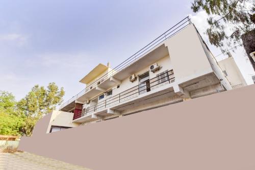 a white house with a balcony and trees at OYO Hotel Paradise Inn in Jodhpur